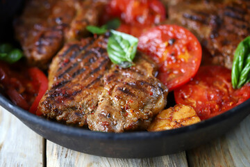 Appetizing juicy grilled steak with grilled vegetables in a pan. Close-up.