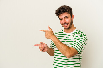 Young caucasian man isolated on white background pointing with forefingers to a copy space, expressing excitement and desire.