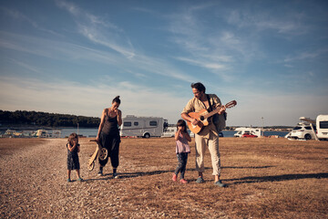 Family on a vacation, singing, playing music on a guitar and enjoying summertime vibes.