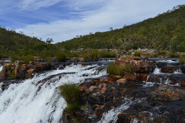 Início da queda da cachoeira com montanha e céu ao fundo
