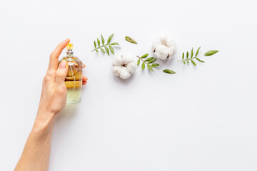 Female hand spray perfume bottle and flow of flowers