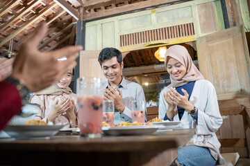 group of young asian people praying together before breaking fast together in the dining room