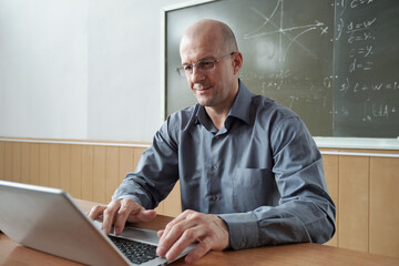 Contemporary teacher using laptop during online lesson in classroom