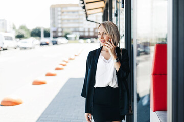 Fototapeta premium A beautiful businesswoman, talking on the phone in the city, holding a folder with documents