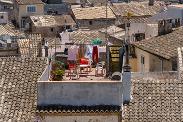 Houses with traditional roof tiles. Detail of the beautiful old town in Arta, Majorca, Spain. Travel scenic. Typical mediterranean cityscape and culture. Drying clothes on a clothesline outdoors.