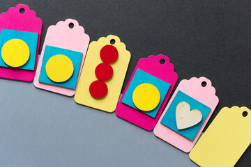 wooden pastel colored chalkboard tags on a duo-toned gray paper background featuring yellow discs, red circles, and a wooden heart