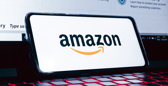  Amazon. A logo da Amazon na tela de um celular que est&aacute; sobre um teclado de notebook com ilumina&ccedil;&atilde;o de leds. Fotografia em ambiente noturno. Site, Com&eacute;rcio eletr&ocirc;nico, online, Venda, Varejo, produto.