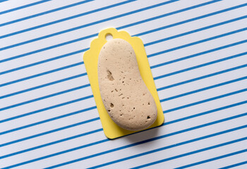 wooden pastel yellow chalkboard tag on a striped paper background featuring an ear-shaped stone