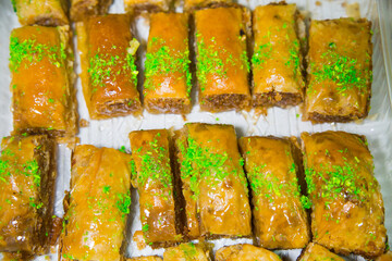 Oriental sweets Baklava made of golden puff pastry with rectangular nuts sprinkled with green pistachio chips. Fruits nuts vegetables berries useful products agriculture.