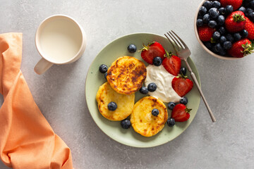 Cottage Cheese Pancake with strawberries, blueberries and sour cream, mug with milk and fresh berries, delicious breakfast, top view