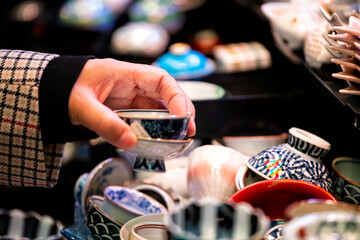 Store display closeup of ceramic pottery with tea cups teacups design and hand person picking...