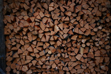 Logs of firewood piled under canopy, closeup.