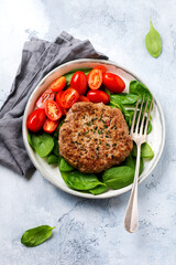 Grilled steak of beef with cherry tomatoes and spinach, garlic, seasonings, peppers and onions. Pleskavitsa traditional Serbian dish. Top view