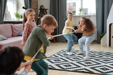 Two teams of kids pulling rope in home environment