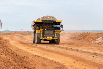 a mining dump truck drives and unloads bauxite minerals
