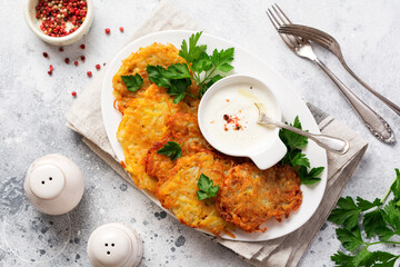 Draniki - potatof ritters, vegetarian potato pancakes, served with fresh herbs and garlic yogurt sauce, top view