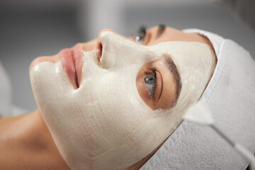 Side view portrait of beautiful young woman on procedure peeling for improvements skin face in beautician. Concept of special professional cosmetology for improvements face and body.