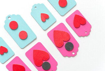 pastel colored wood chalkboard tags loosely arranged in a classic arragement with hand painted red hearts and black discs on a white paper background