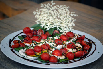 healthy eating, mozzarella - tomatoes in olive oil and balsamic vinegar and basil with elder blossoms decor
