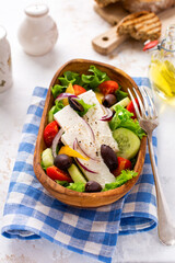 Fresh greek salad with tomato, cucumber, bel pepper, olives and feta cheese on wooden plate. Traditional Greek dish. Healthy food, top view