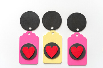 Obraz premium pastel colored wood chalkboard tags loosely arranged in a classic arragement with hand painted red hearts and black discs on a white paper background