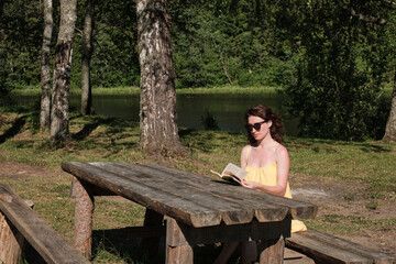 Fototapeta premium The girl sits at the table and reads a book. Education outside the city