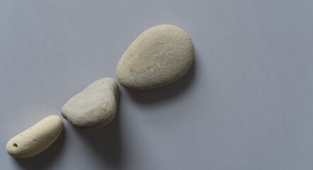 Fototapeta na wymiar three stones arranged on a gray background 