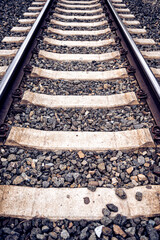 Closeup looking down on symmetric train rails with rocks in Sacramento, California