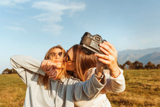 Cheerful woman taking selfie with vintage camera