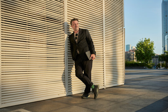 Business man standing up outside of office building in sunset time