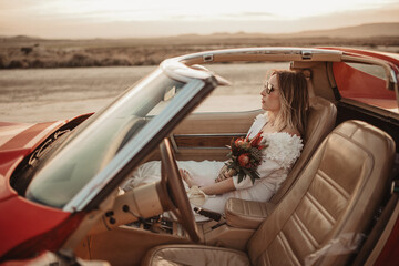 Bride sitting in luxury car in desert
