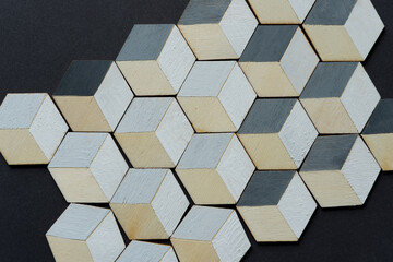 3d wooden cubes (hexagons) hand painted in white and various shades of gray acrylic paint, loosely arranged on a medium gray paper background, and photographed from above in a flat lay style with ambi
