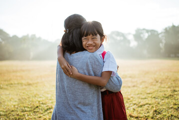 asian mother embrace and hug her daughter wearing uniform when going to school in the morning