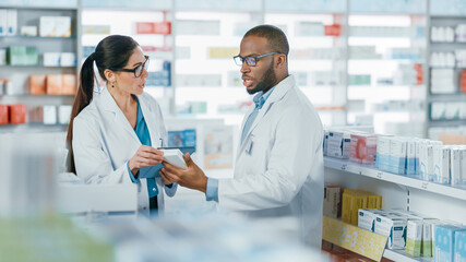 Pharmacy: Black Male and Caucasian Female Pharmacists Use Digital Tablet Computer Talk about...