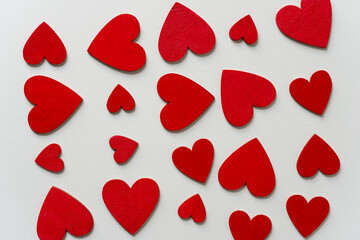 hand painted wooden shapes (hearts) in cadmium deep red acrylic paint on a light background - photographed from above with ambient light
