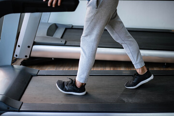 Training gym concept a male teenager wearing long pants and black trainers walking on a treadmill...