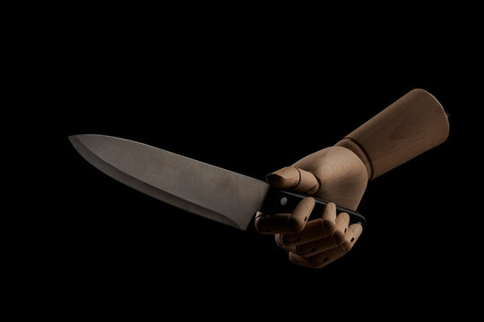 Crop wooden hand with sharp knife in studio
