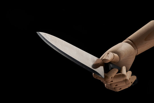 Crop wooden hand with sharp knife in studio