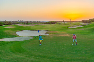 Active senior couple playing golf at sunset