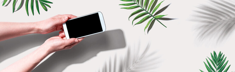 Smartphone with tropical palm leaves and shadow