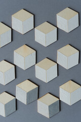 3d wooden cubes (hexagons) hand painted in white and various shades of gray acrylic paint, loosely arranged on a medium gray paper background, and photographed from above in a flat lay style with ambi