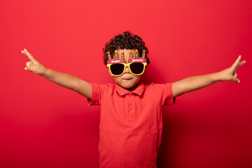 Cool boy in birthday glasses on red background