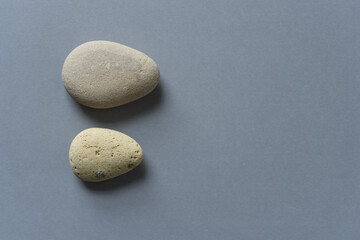 Fototapeta na wymiar two tear shaped stones on gray paper