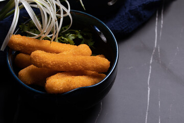 Chicken nuggets sticks in a cup on black background.