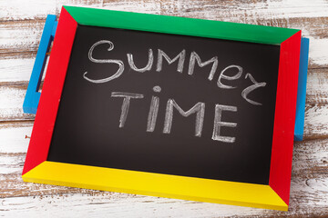 Blackboard with text it's summer time on wooden desk