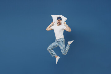 Full length young man 20s in pajamas jam sleep mask rest relaxing at home pillow cover ears from...