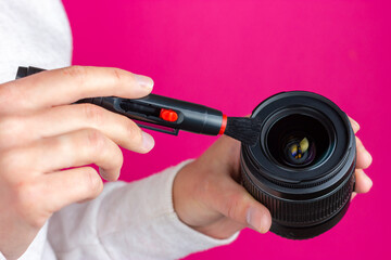 Optics cleaning. Service of photographic equipment. Photo lens and cleaning tool in female hands.