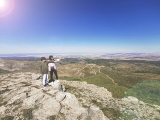 Fototapeta premium Hiking and travel. Mother and son admiring the views atop a mountain top.