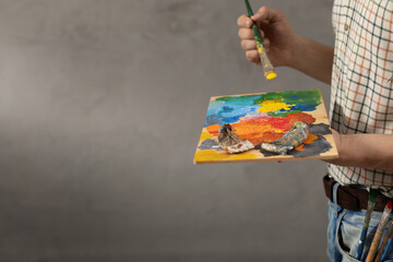 Man painter holding paint palette with paint brush. Young artist painting in creative studio