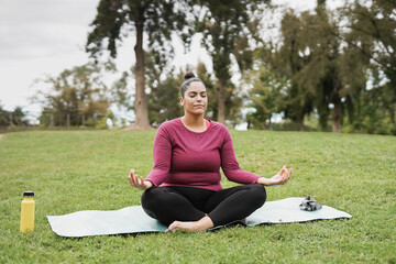 Curvy woman doing meditation at city park - Healthy lifestyle and life balance concpet
